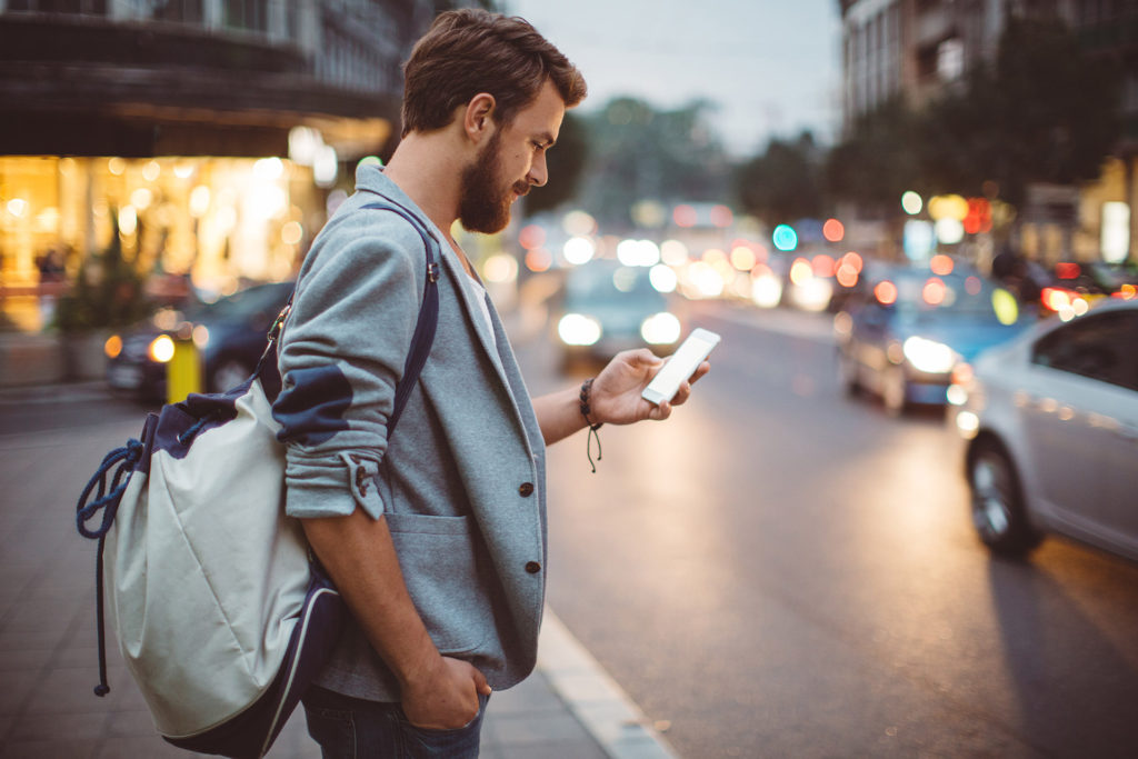 guy looking at his phone on busy street